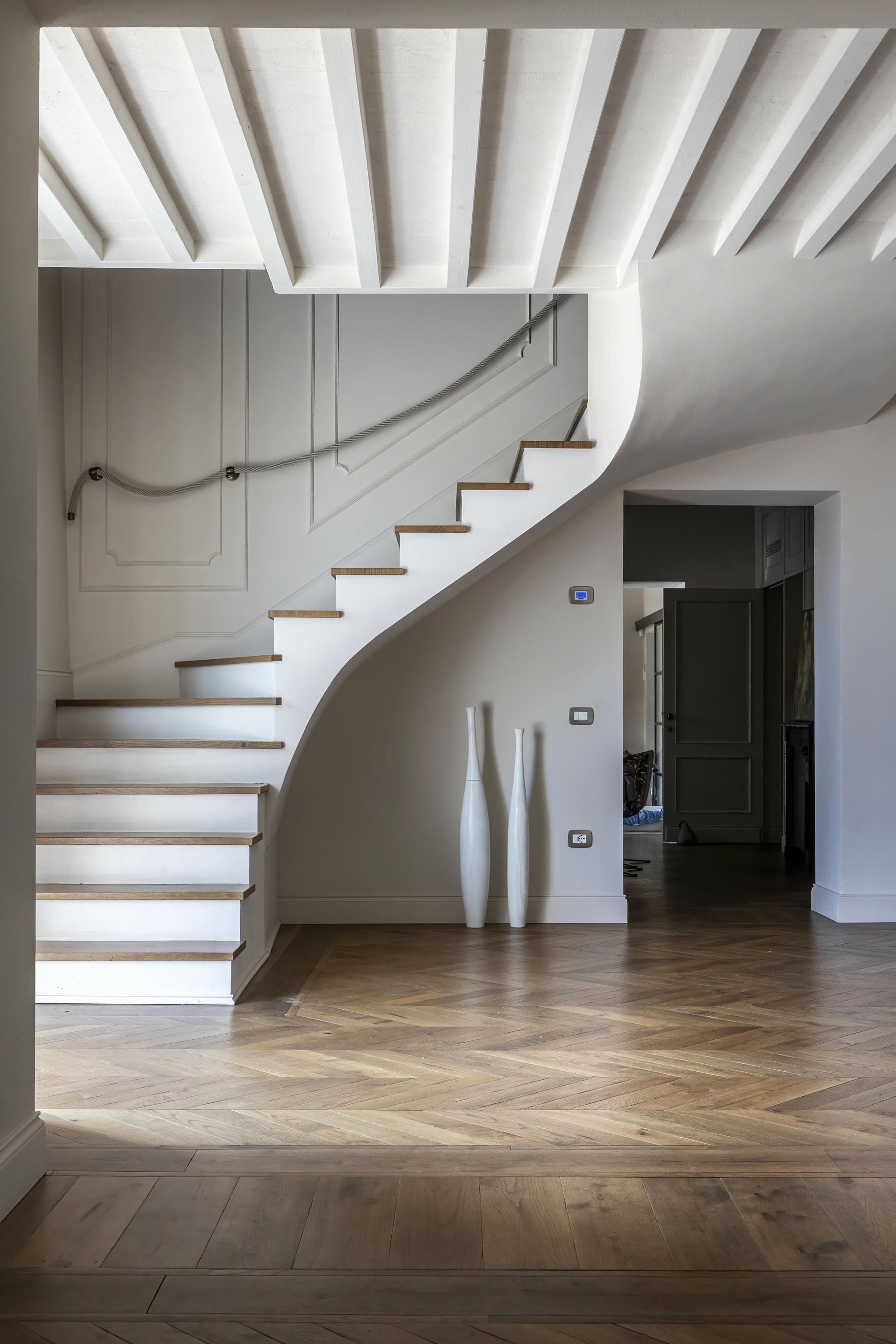 Ingresso residenziale con scala architettonica e pavimento in parquet